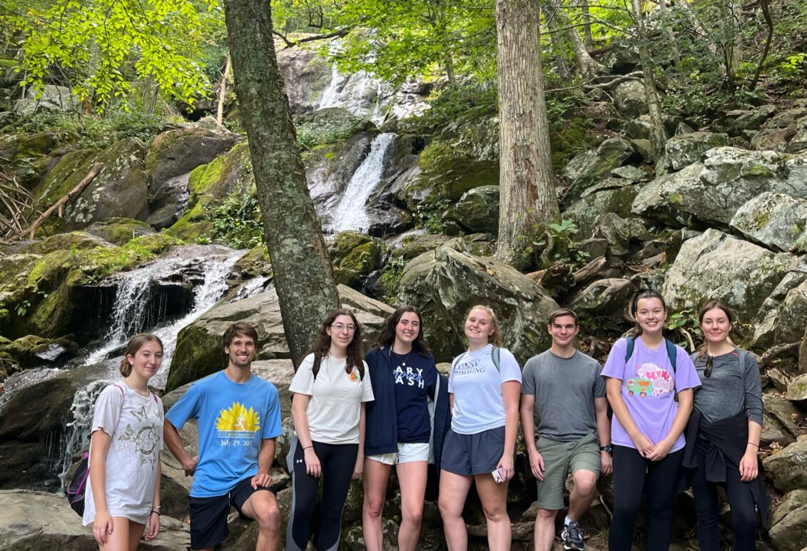 Students on a hike standing in front of a waterfall