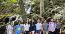 Students on a hike standing in front of a waterfall