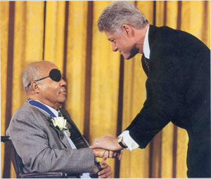 James Farmer shaking hands on stage with President Bill Clinton at the ceremony for the Medal of Freedom in 1998.