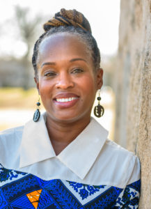 Smiling woman leaning against a tree, Rev. Dr. LaKeisha Cook