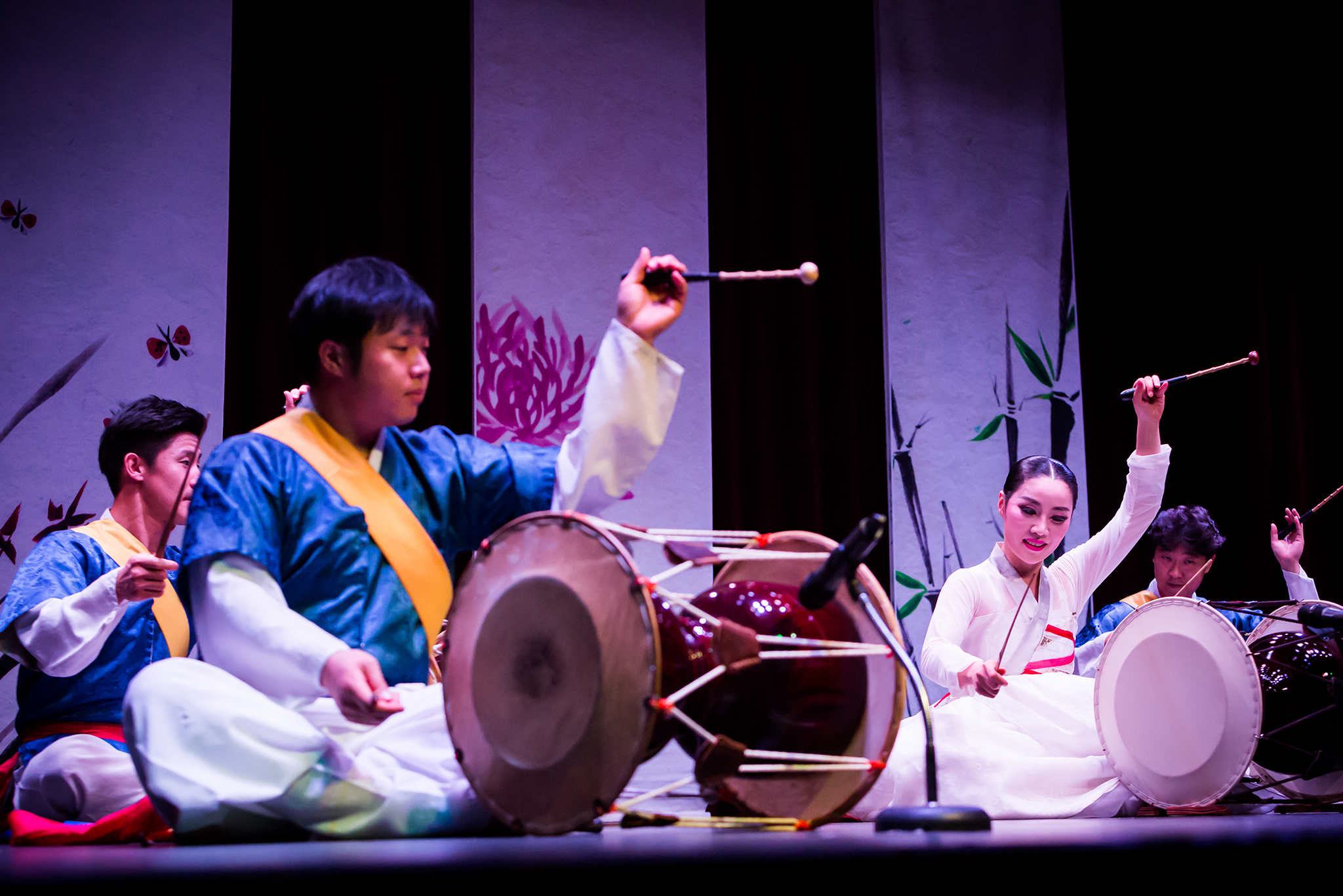 A group of performers sitting on a stage playing various percussion instruments